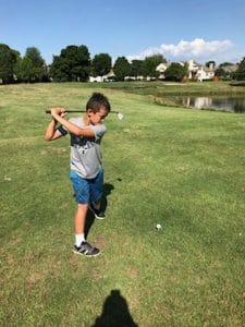 camper swinging golf club at summer camp